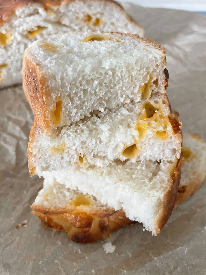 Three slices of Easy Cheesy Bread stacked offset on each other on parchment paper.