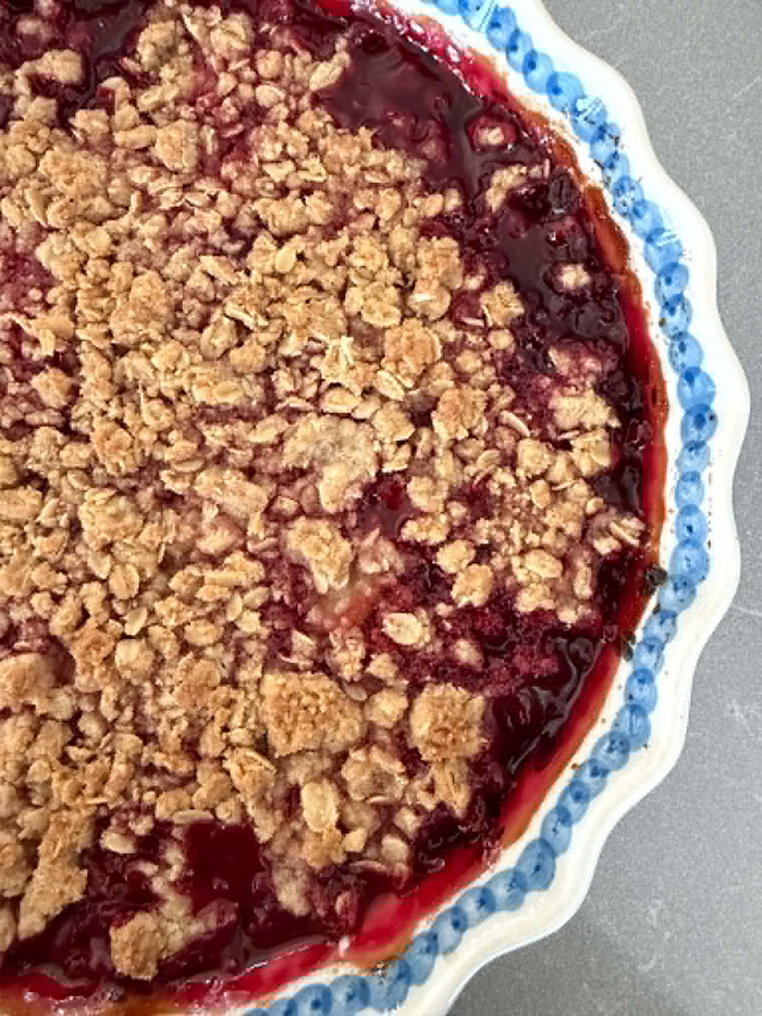 Raspberry Rhubarb Crisp in a round deep-dish baking dish with a scalloped edge.