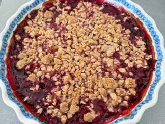 A round baking dish with scalloped edges of Raspberry Rhubarb Crisp.