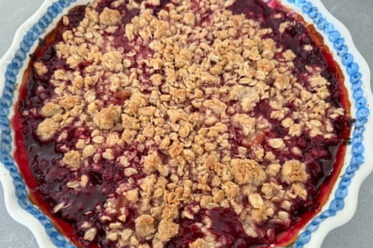 A round baking dish with scalloped edges of Raspberry Rhubarb Crisp.