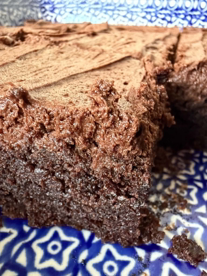 A closeup photo of a corner of a 9x13 baking dish of sliced frosted brownies with a couple of brownies missing.