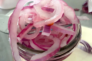 A small jar of overflowing pickled red onions.