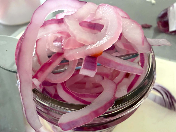 A small jar of overflowing pickled red onions.