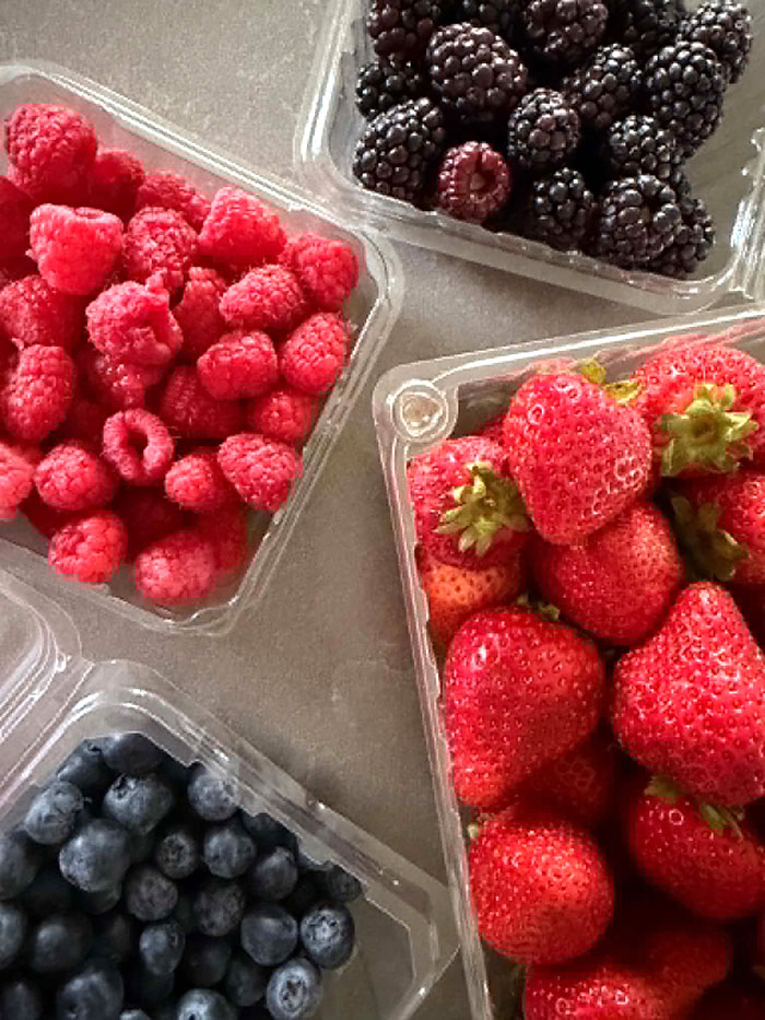 Plastic containers of raspberries, blackberries, strawberries, and blueberries.