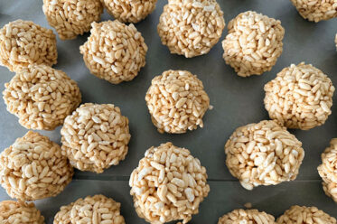 Caramel puffed rice balls sitting on a sheet of wax paper.