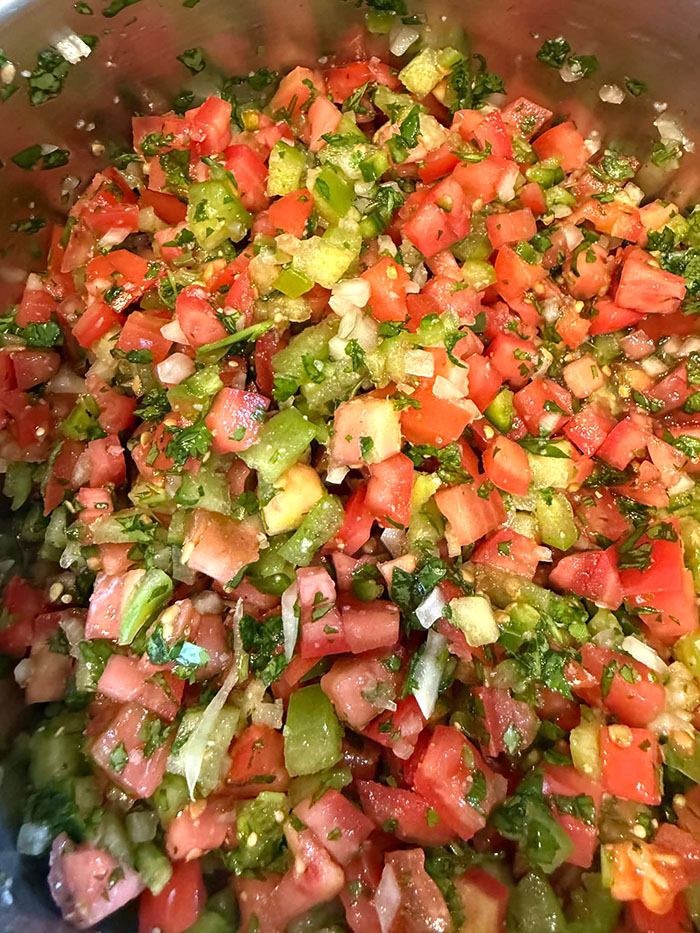 Pico de gallo with tomatillos in a metal mixing bowl.