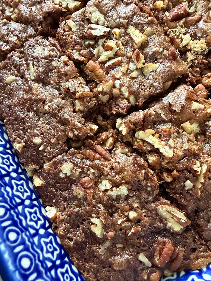 A partial closeup picture of sliced chocolate zucchini cake with pecan streusel in a 9x13 baking dish.
